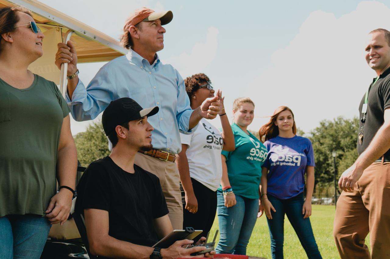 Male and female students learning aviation outside with male faculty member